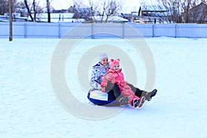 Mom and daughter ride a tubing in winter.