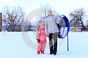 Mom and daughter ride a tubing in winter.