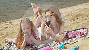 Mom and daughter on the river bank eat ice cream. Outdoor recreation