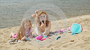 Mom and daughter on the river bank eat ice cream. Outdoor recreation