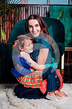 Mom and daughter in rubber gloves hug sitting on the floor after cleaning