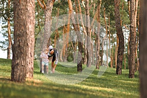 Mom and daughter are running in the forest. The sisters are playing hide and seek in the forest. Mother`s day, women`s holiday