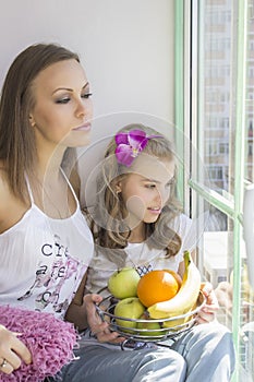 Mom and daughter sit near the window.