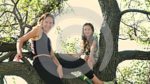 Mom and daughter sitting together on a tree. Happy motherhood, spending time together.