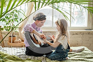 mom and daughter on the sofa, playing the guitar. a woman and a girl compose music, songs togethe