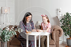 Mom and daughter spend time together, sit on the couch, chatting and playing with toy animals. Leisure mothers and daughters