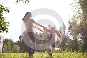 Mom and daughter spinning on the lawn holding hands