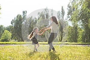 Mom and daughter spinning on the lawn holding hands