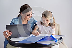 Mom and daughter student learning school lessons together at home