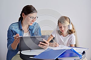 Mom and daughter student learning school lessons together at home
