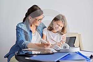 Mom and daughter student learning school lessons together at home