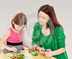 Mom and daughter at the table playing educational games