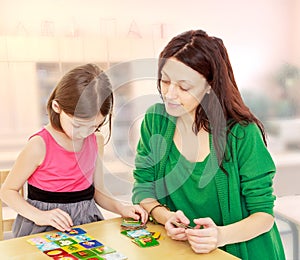 Mom and daughter at the table playing educational games