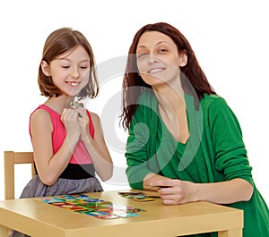 Mom and daughter at the table playing educational games