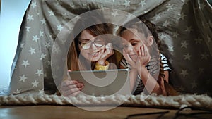 Mom and daughter under the blanket with a digital tablet. kid dream online video games at concept. Mom and daughter