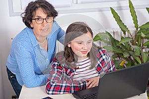 Mom and daughter using a laptop at home
