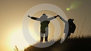 Mom and daughter on vacation traveling and dancing on mountain. Woman with raised hands on top of mountain looking at