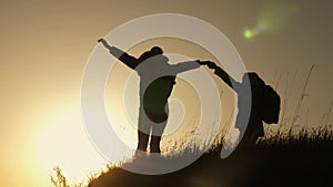 Mom and daughter on vacation traveling and dancing on mountain. Woman with raised hands on top of mountain looking at