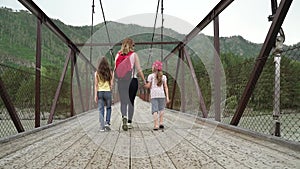 Mom and daughter are walking along the bridge in the rain. The family travels in the mountains. Young woman tourist with