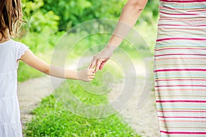 Mom and daughter are walking along the road holding hands