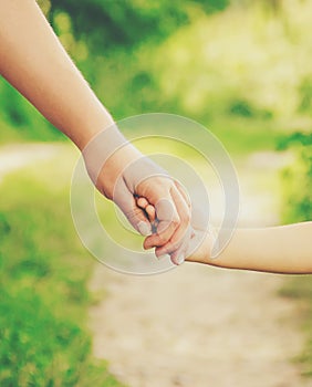 Mom and daughter are walking along the road holding hands