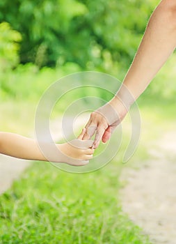 Mom and daughter are walking along the road holding hands