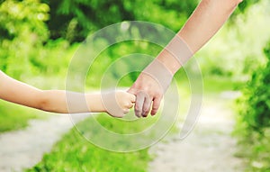 Mom and daughter are walking along the road holding hands. Selective focus.