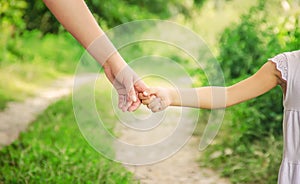 Mom and daughter are walking along the road holding hands. Selective focus.