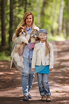 Mom and daughter walking in the park with the same two Shih Tzu dogs