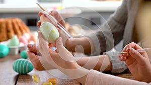 Mom and daughter wearing bunny ears decorating Easter eggs.