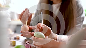 Mom and daughter wearing bunny ears decorating Easter eggs.