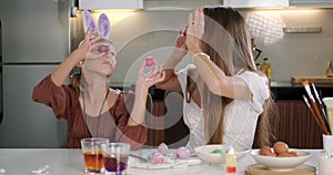 Mom and daughter wearing hair holders with bunny ears decorate Easter eggs.