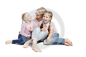 Mom and daughters are sitting and laughing. Love and tenderness. Isolated over white background