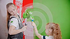 Mom and doughter play with paint fun while painting walls in new apartments