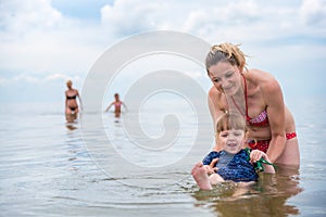 Mom entertains little daughter on the water, sea, summer holidays, rest and recreation photo