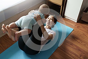 Mom exercising playing with her baby at home, Asian young mother lifting little boy in the air, Yoga, Workout