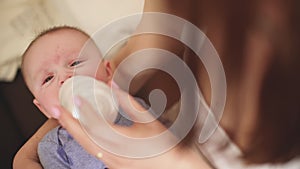 Mom feeding infant baby boy from bottle