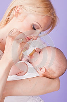 Mom feeds the baby from the bottle with teat