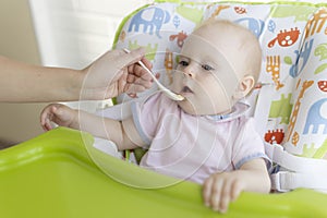 Mom feeds the baby with a spoon