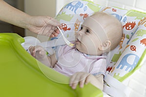 Mom feeds the baby with a spoon