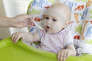 Mom feeds the baby with a spoon