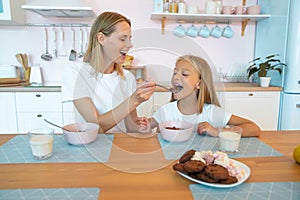 Mom feeds her beautiful daughter with chocolate flakes. have a good time together, dressed alike