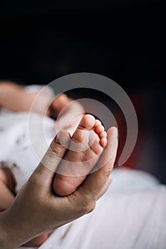 Mom gently hold baby`s foot in her hand