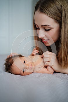 mom gently looks at the baby on bed. maternal love and care. care for newborns