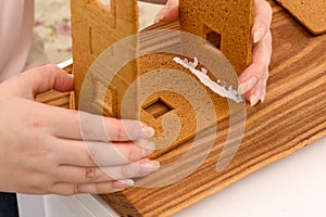 Mom glues the details gingerbread house with protein cream. female hands hold details close-up