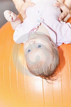 Mom with happy baby doing exercises at gymnastic ball