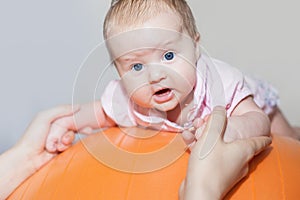 Mom with happy baby doing exercises at gymnastic ball