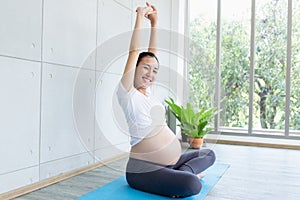 Mom is having fun doing yoga. Pregnant woman doing morning exercises at home