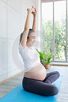 Mom is having fun doing yoga. Pregnant woman doing morning exercises at home