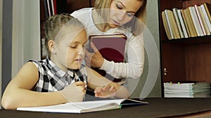 Mom helping her daughter do homework. schoolgirl makes lessons